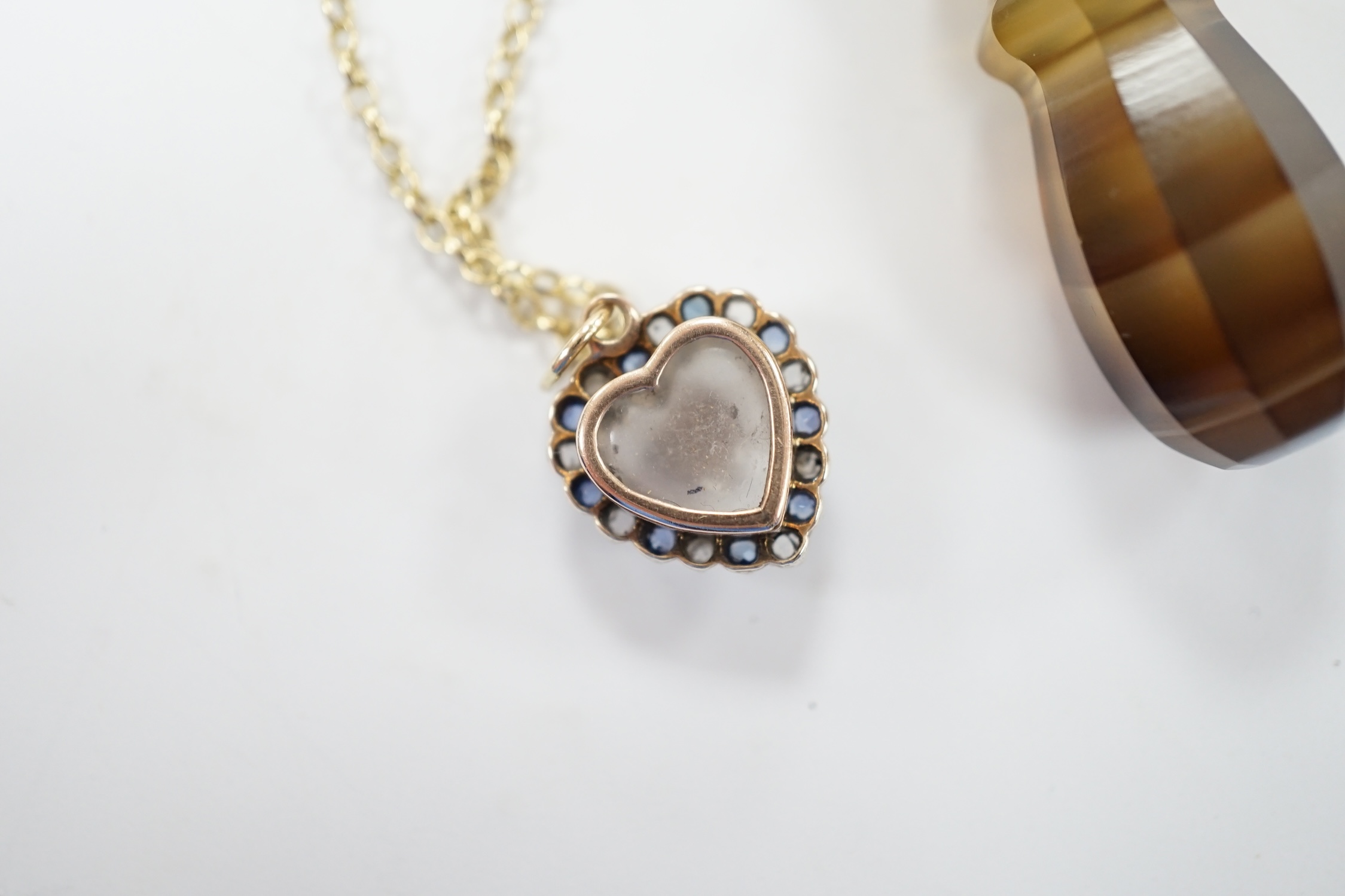 An early 20th century yellow metal, moonstone, sapphire and rose cut diamond set heart shaped pendant, 12mm on a yellow metal chain, together with a yellow metal mounted banded agate pendant, on a 9c chain. Fair conditio
